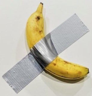 A yellow banana attached to a white wall by a piece of silver-colored duct tape A yellow banana attached to a white wall by a piece of silver-colored duct tape