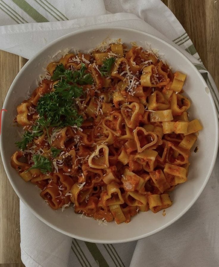 This may contain: a white bowl filled with pasta covered in sauce and parmesan cheese