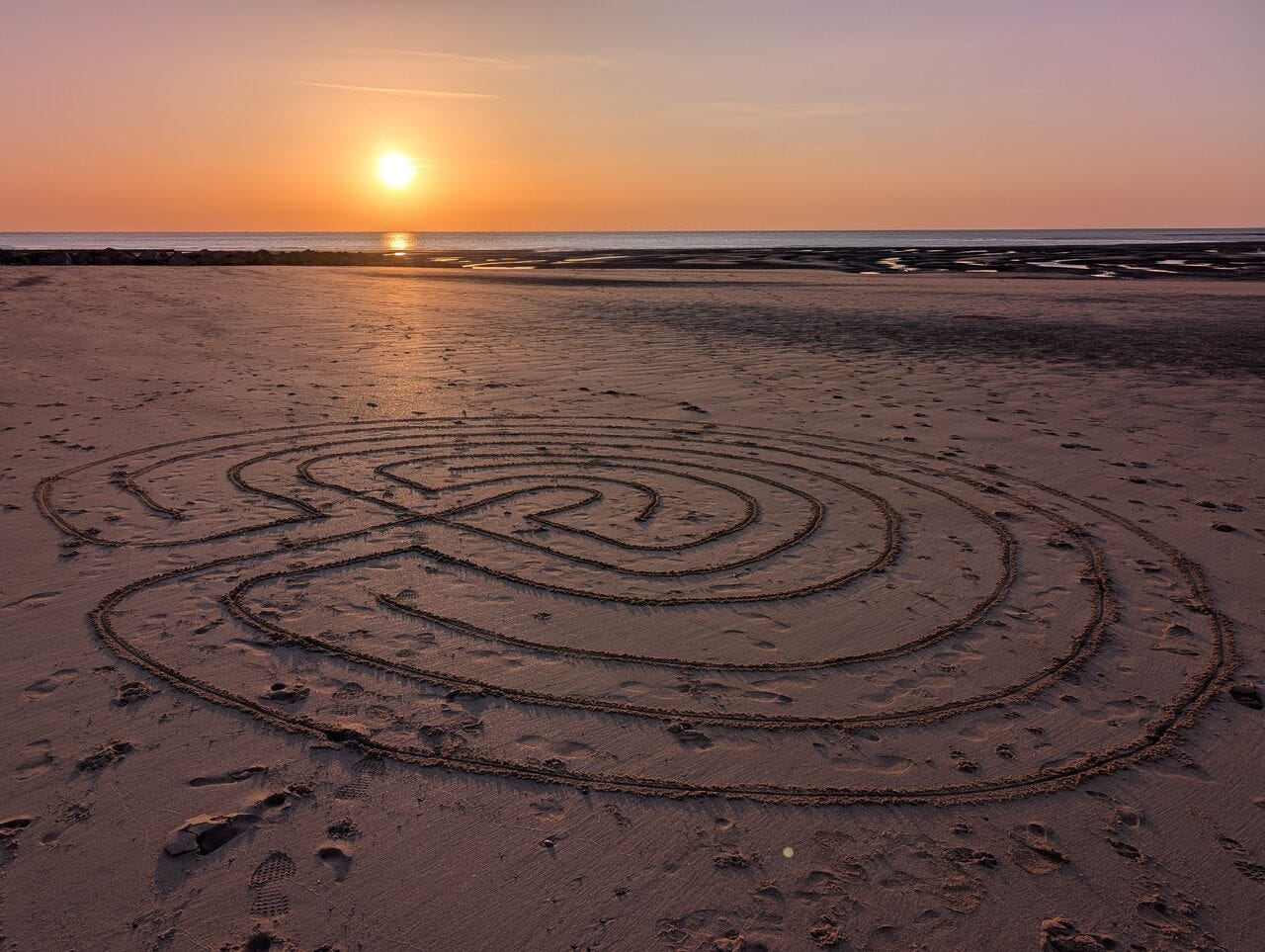 Classical labyrinth drawn on a beach at sunset