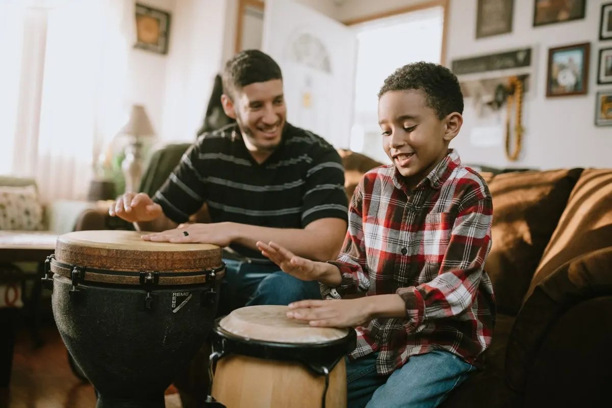 Father and son playing drums together in their living room.