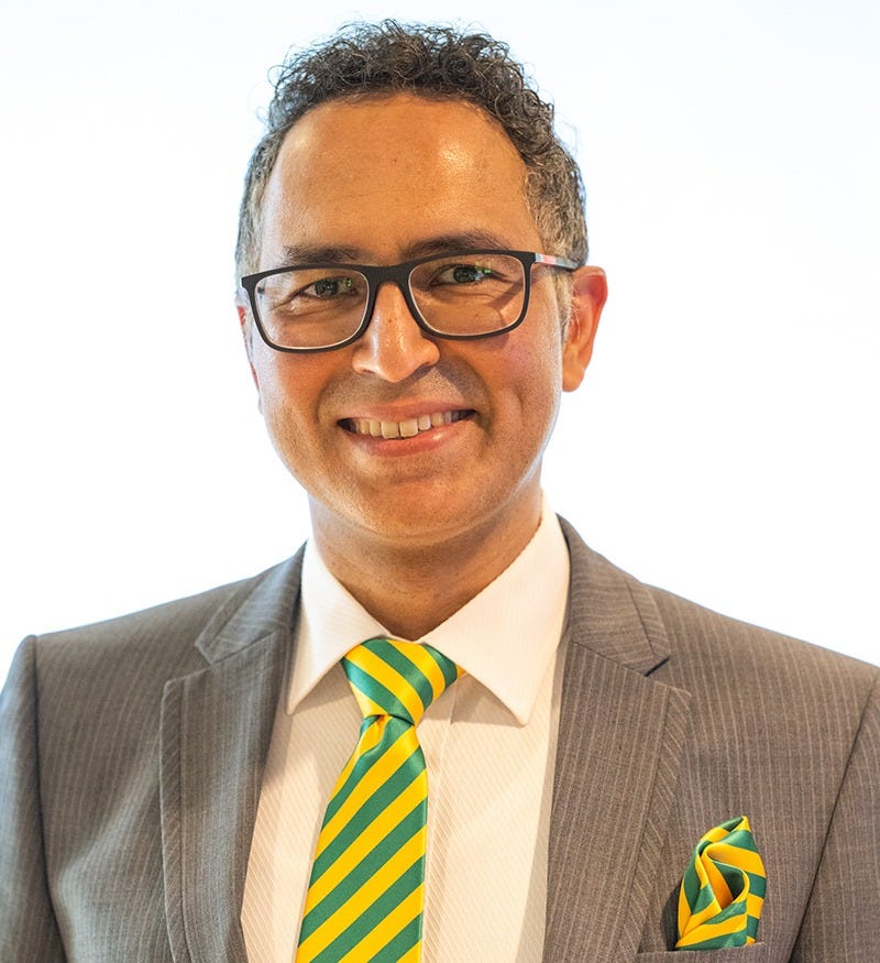 Head and shoulders photograph of a smiling man in a suit wearing glasses Head and shoulders photograph of a smiling man in a suit wearing glasses