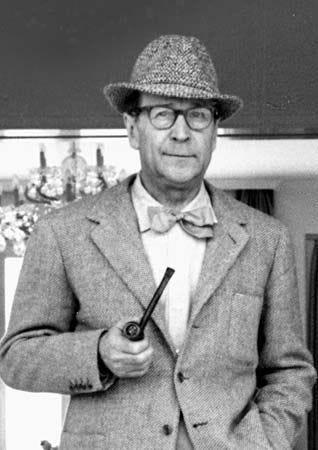 This may contain: an old man in a suit and hat holding a pipe