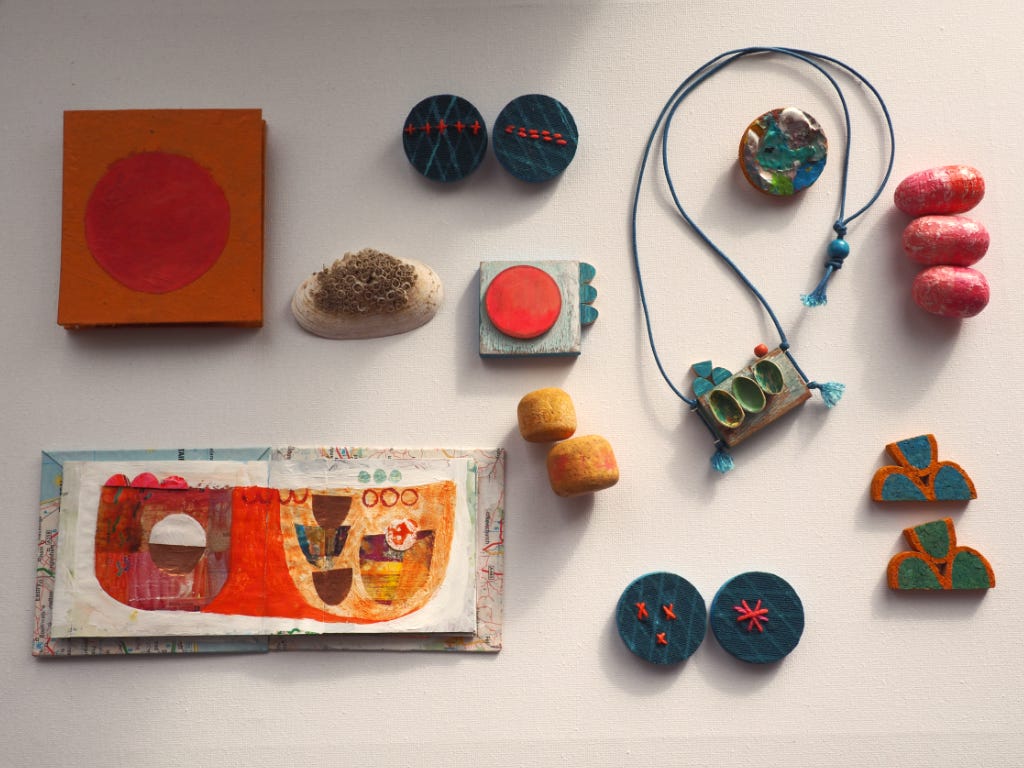 Handmade sketchbooks, handmade accessories in progress and a shell on a white background.
