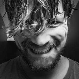 black and white photo of a man with messy hair smiling at the camera