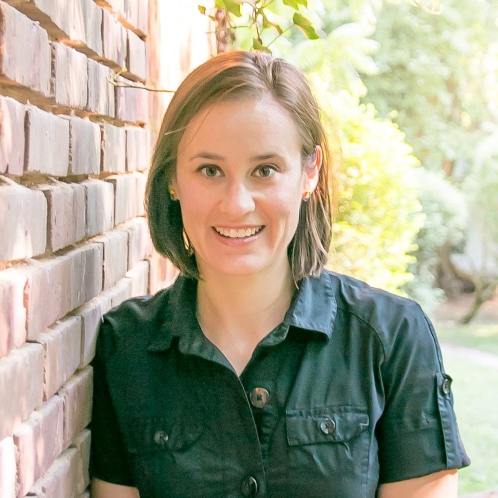 Summer Hill-Vinson is seen standing near a brick wall in a darkly colored button-down short-sleeved shirt, in front of a green outdoor space. Summer Hill-Vinson is seen standing near a brick wall in a darkly colored button-down short-sleeved shirt, in front of a green outdoor space.