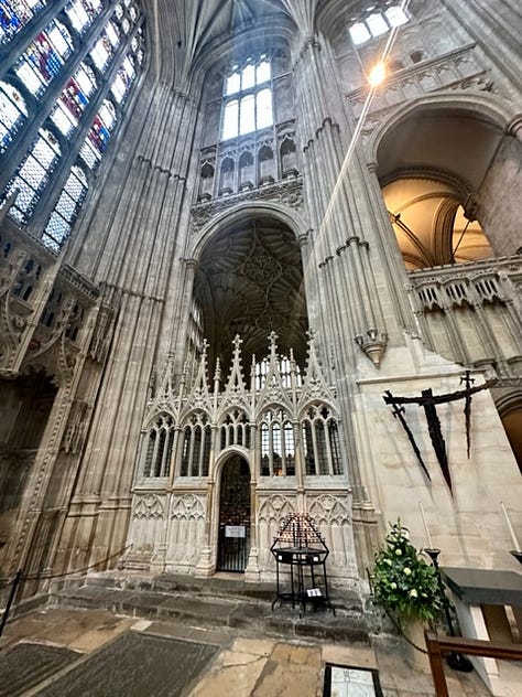White woman poses awkwardly in front of cathedral and gardens