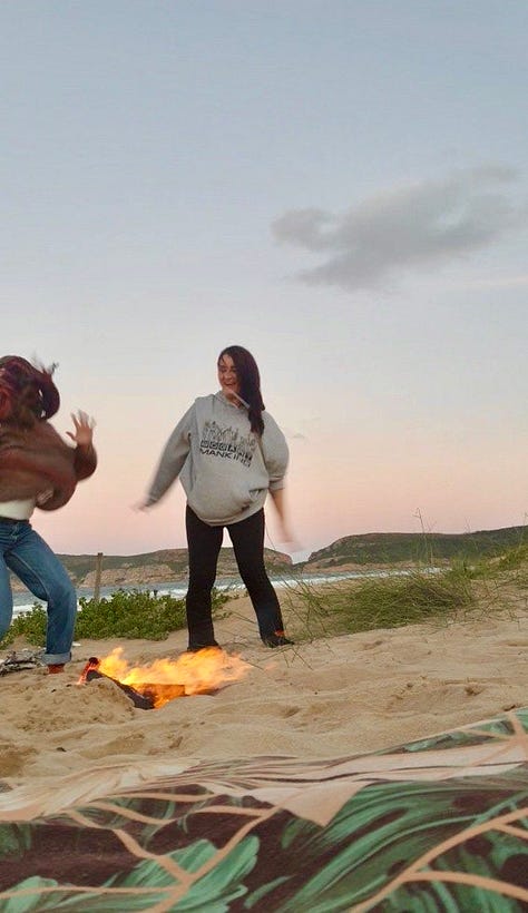 two women having fun behind a fire on the beach
