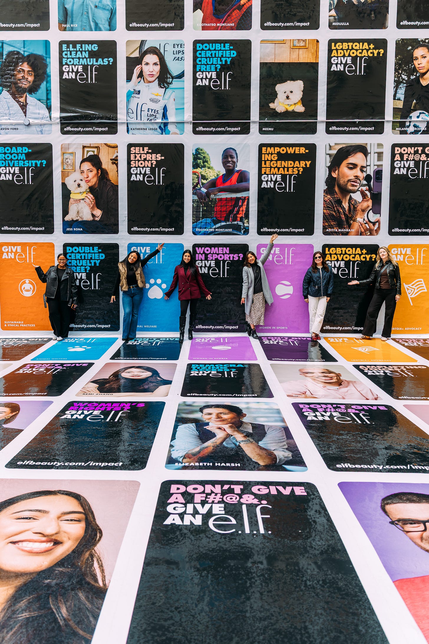 e.l.f. employees at an outdoor activation with signs reading give an e.l.f. e.l.f. employees at an outdoor activation with signs reading give an e.l.f.