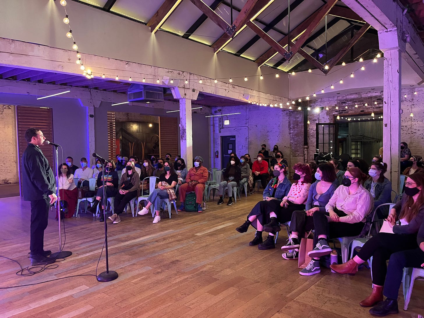 Derrick at a microphone performing in front of an audience.