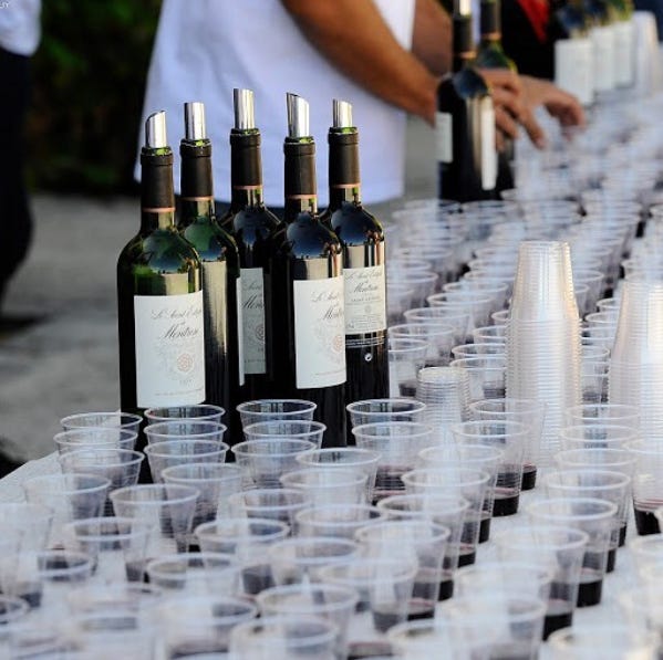 Runners stop at a wine tasting station during the Médoc Marathon, where local wines are served along the course. Runners stop at a wine tasting station during the Médoc Marathon, where local wines are served along the course.