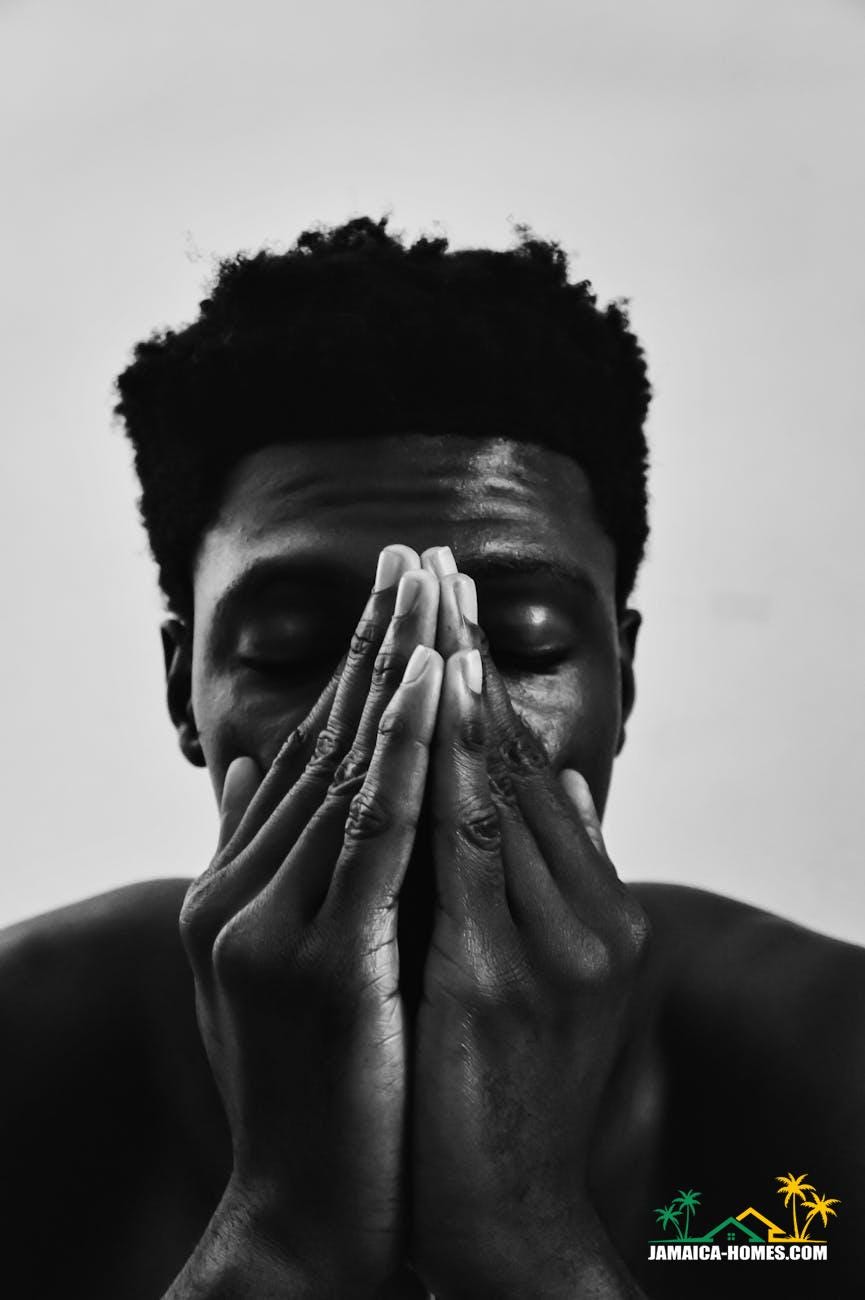 grayscale photo of man covering his face with his hands