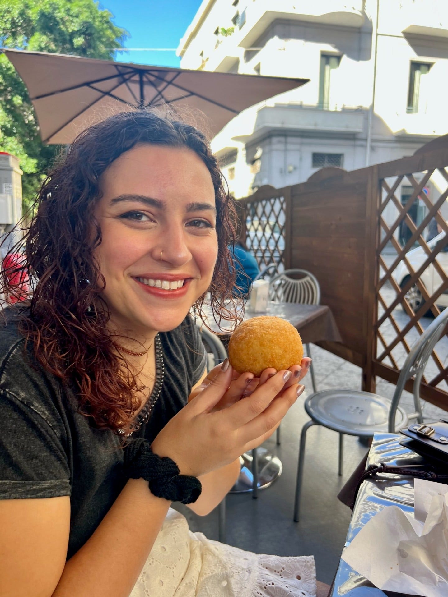 find best local food when you travel - posing happily with an Arancini from a local cafe in Catania, Sicily