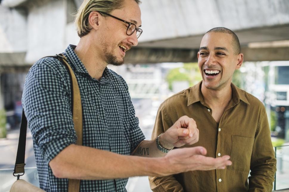 Two men smiling and talking with each other
