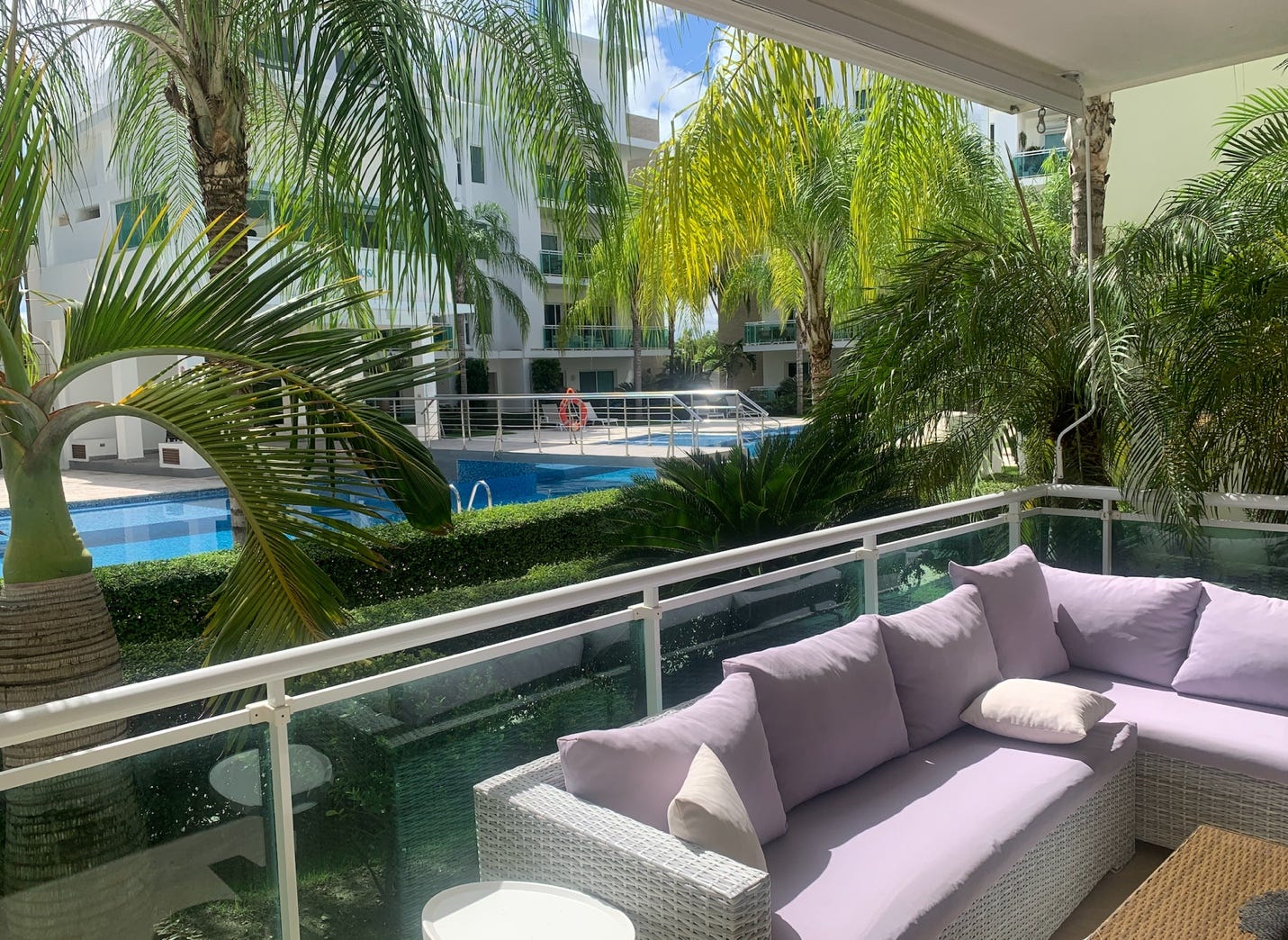 A couch on a balcony with palm trees and pool

AI-generated content may be incorrect.