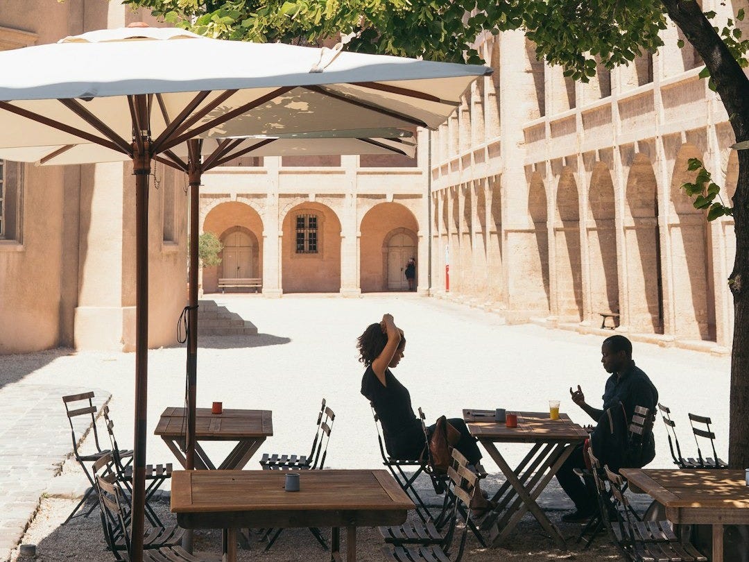 man and woman sitting on chair while dining under patio umbrella