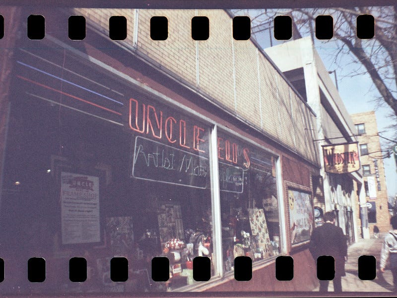 color photo of storefront with neon signage and film sprocket holes
