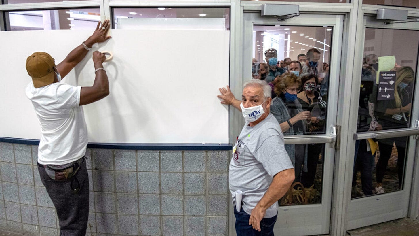 Poll workers board up windows so ballot challengers can't see into the ballot counting area at the TCF Center where ballots are being counted in downtown Detroit, Michigan November 4,2020. - Democratic presidential challenger Joe Biden on November 4 neared the magic number of 270 electoral votes needed to win the White House with several battleground states still in play, as incumbent President Donald Trump challenged the vote count.