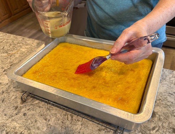 Brushing lemon glaze over the warm cake