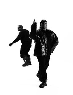 This may contain: two men in black and white are walking with one holding his hand up to the side