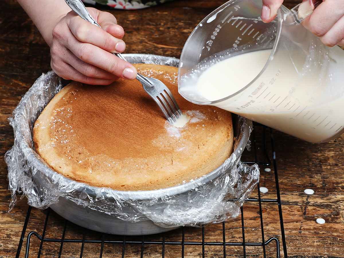 Pouring tres leches mixture on cake
