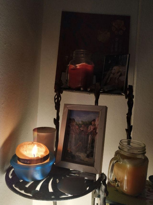 An altar with three lit candles and photos of a dog and of children praying. An altar with three lit candles and photos of a dog and of children praying.