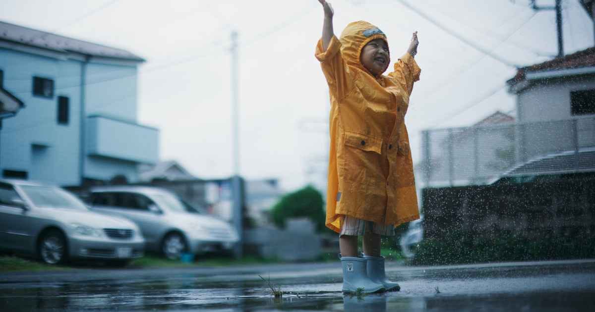Child in yellow raincoat enjoying the rain