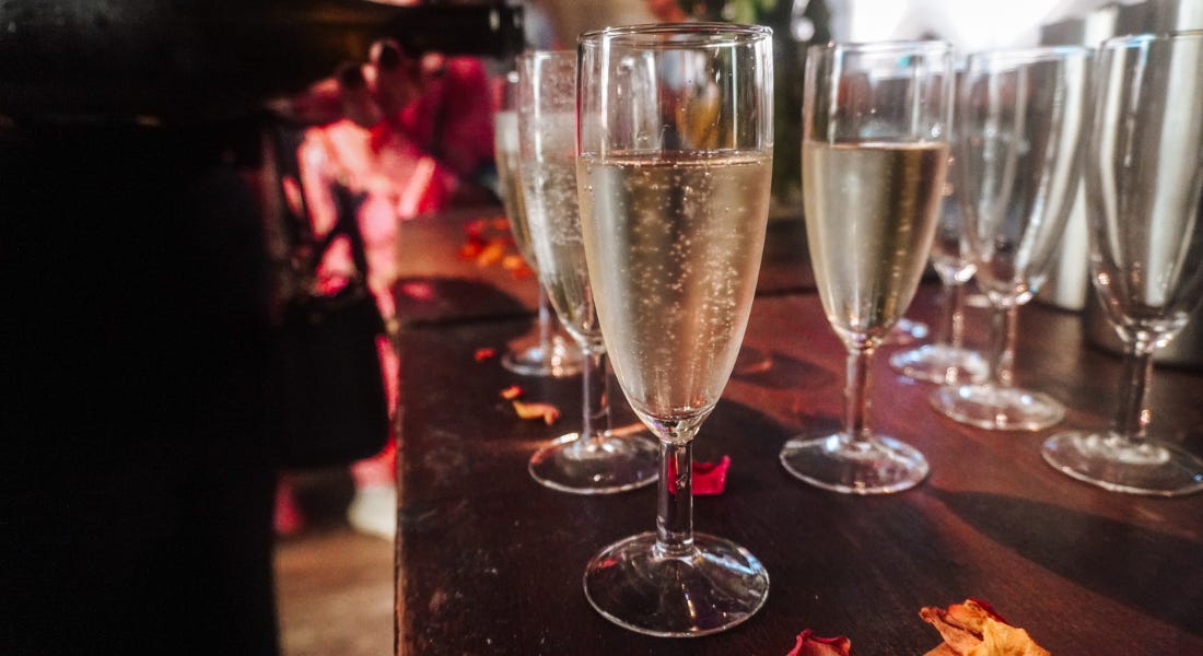 A dark wooden table with glasses of prosecco on it A dark wooden table with glasses of prosecco on it