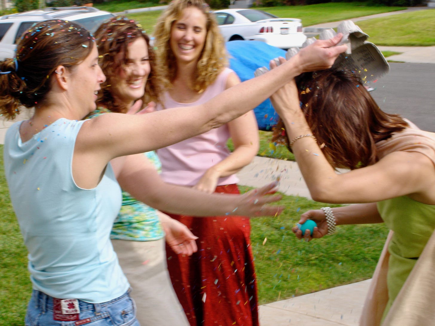 Women laughing during a confetti egg fight at Easter — the family tradition behind The Dinner Bell Hearth Easter post