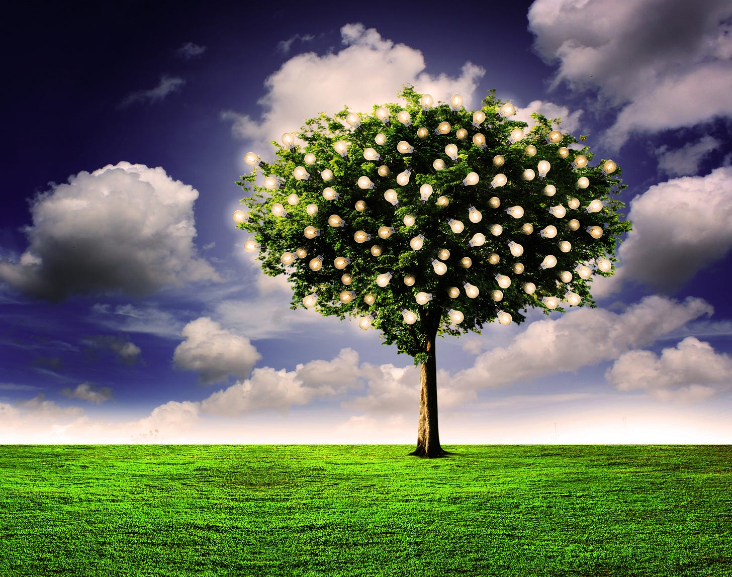 A tree with glowing light bulbs growing like fruit among its green leaves stands alone on a plain of grass under a cloudy deep-blue sky.