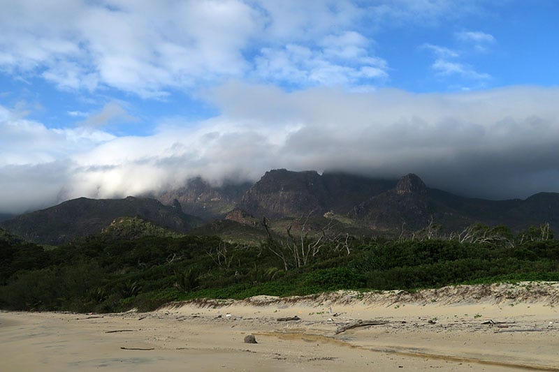 Stretch of beach in front of a mountain, covered with clouds. Stretch of beach in front of a mountain, covered with clouds.