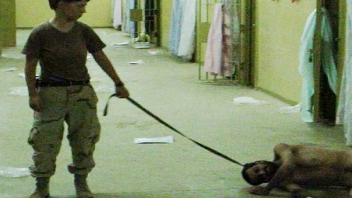 Disturbing image of woman in military fatigues with a naked man on the floor, leashed around his neck. Disturbing image of woman in military fatigues with a naked man on the floor, leashed around his neck.