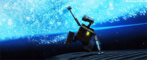Gif da WALL•E con il robot WALL•E che fluttua nello spazio profondo sopra la superficie di un'astronave. Dietro di lui, una scia luminosa di cristalli di ghiaccio azzurri brilla intensamente contro il vuoto blu scuro dello spazio, evocando un senso di meraviglia.