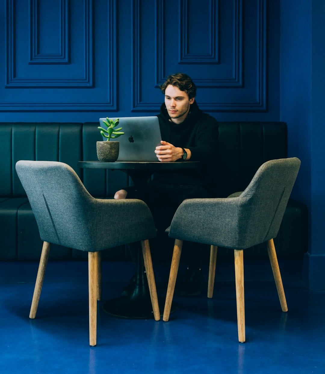 man sitting on couch with looking at his MacBook on table man sitting on couch with looking at his MacBook on table