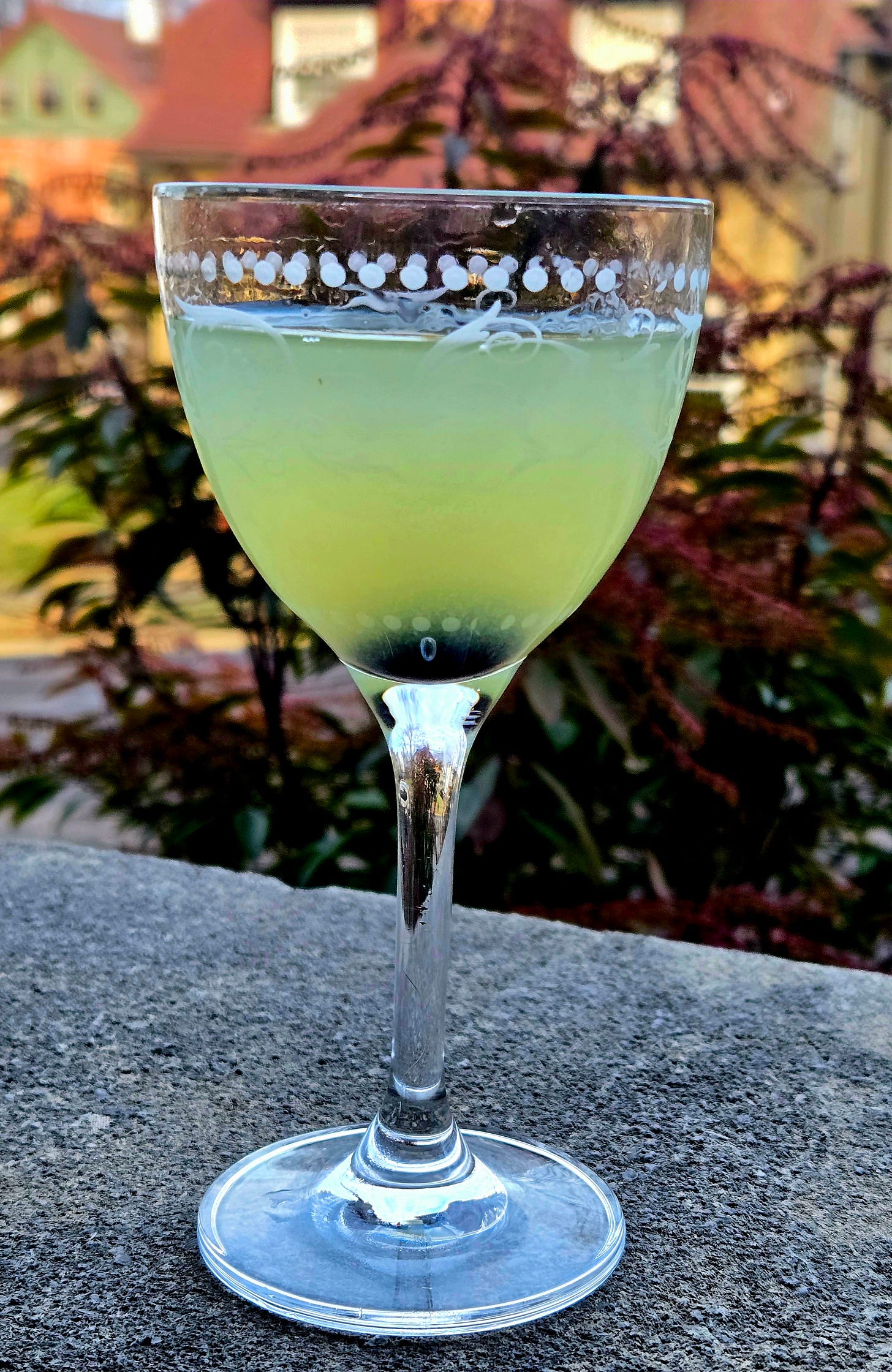 The Last Word cocktail in a Nick and Nora glass with Luxardo Cherry garnish atop a stone wall. The Last Word cocktail in a Nick and Nora glass with Luxardo Cherry garnish atop a stone wall.