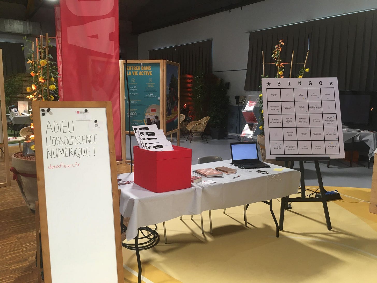Photo du stand Adieu à l'obsolescence numérique, une table avec des BD, des livres et une présentation sur le sujet, un bingo géant pour participer.