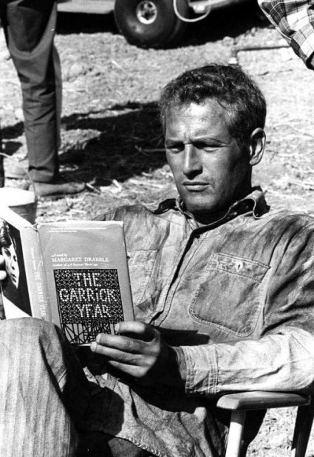 This may contain: a man sitting in a chair reading a book This may contain: a man sitting in a chair reading a book