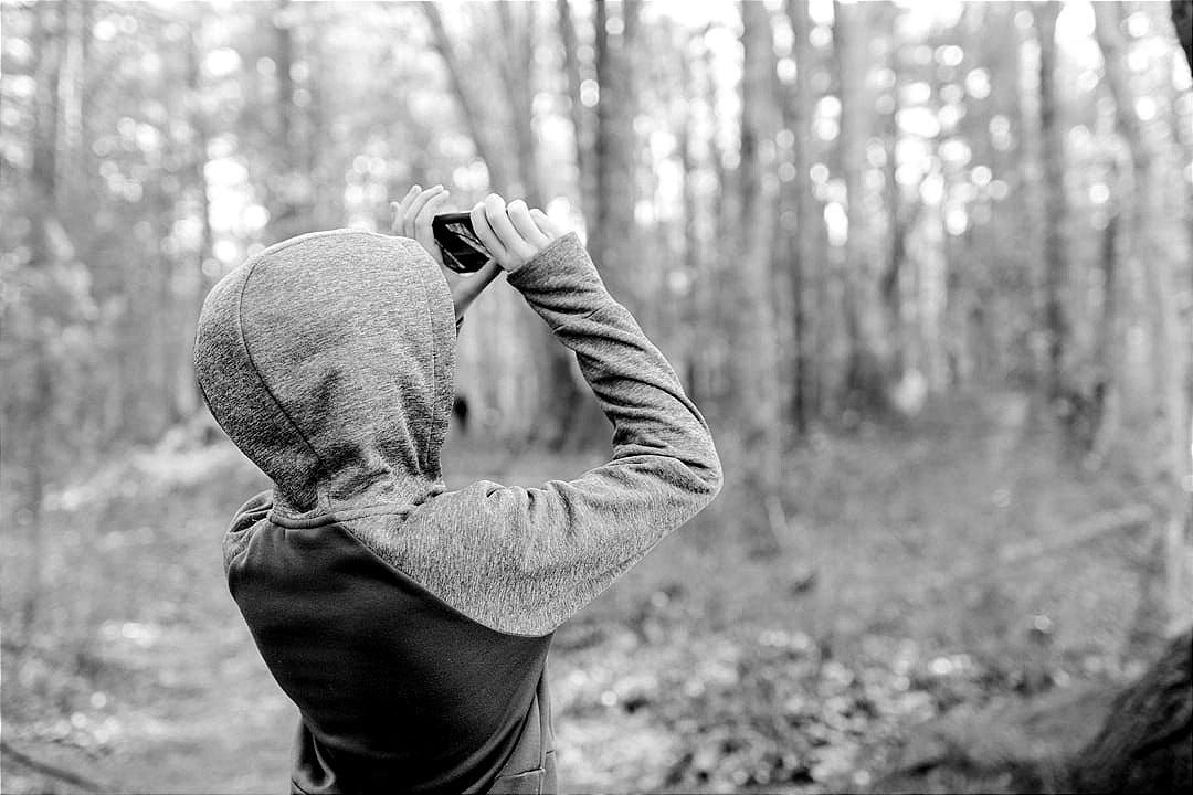 man in gray sweater holding black camera man in gray sweater holding black camera