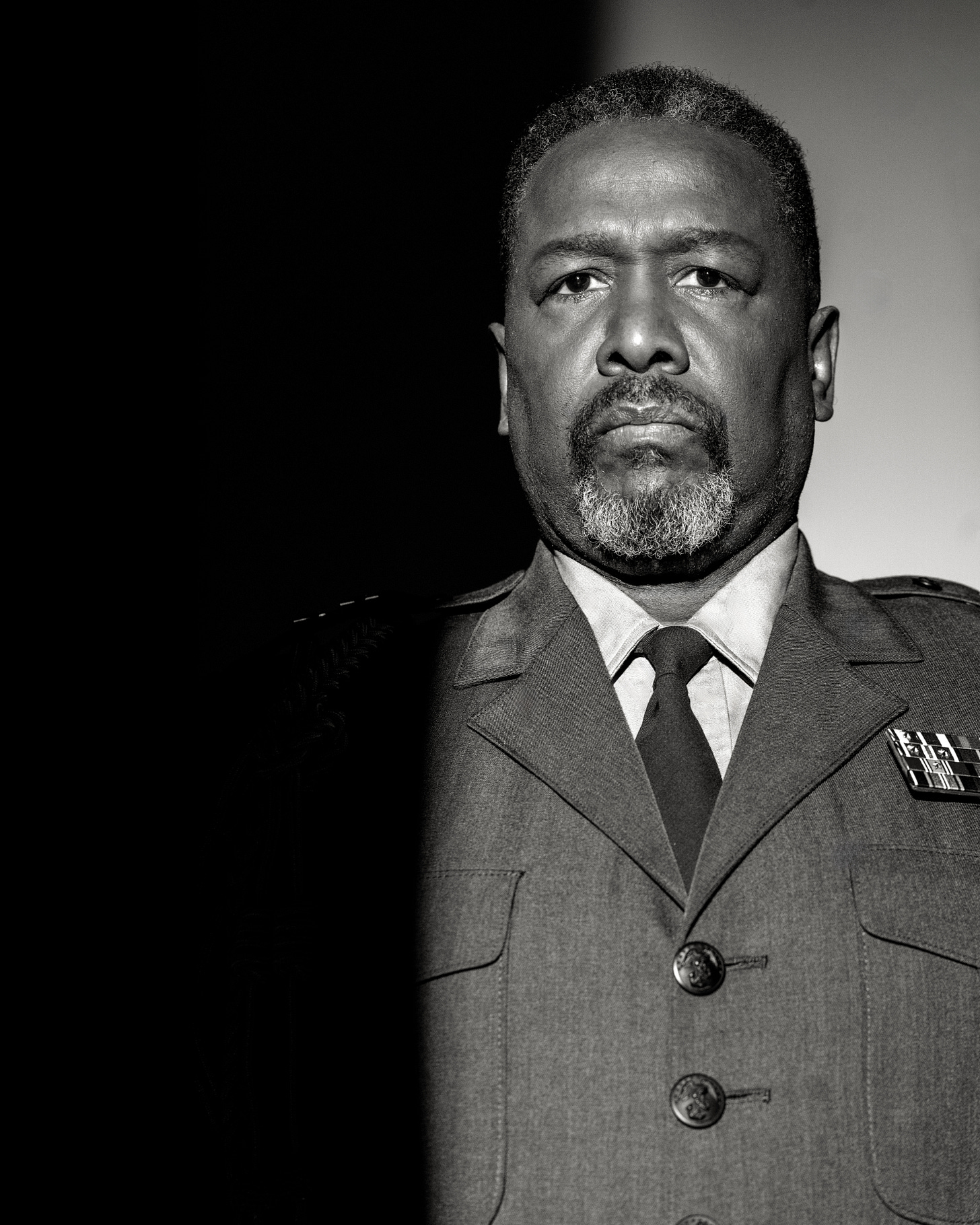 Wendell Pierce in costume for Othello, facing forward in military dress under stark black-and-white lighting.
