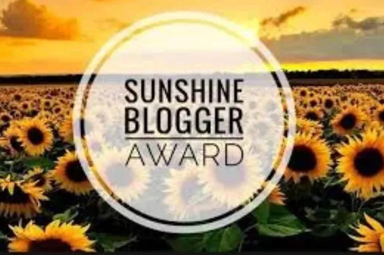 Sunshine Blogger Award logo with field of sunflowers in the background.