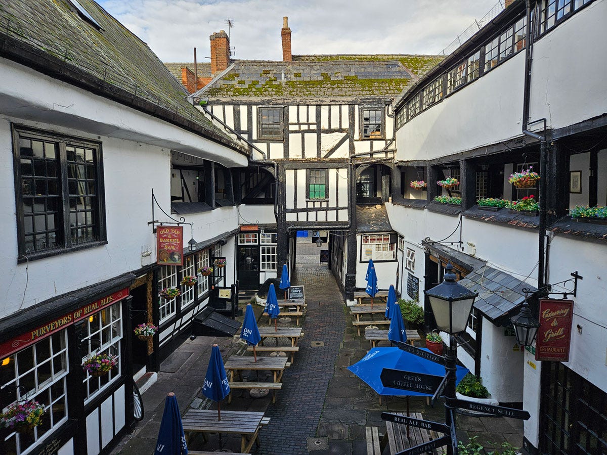 Looking down from the balcony onto the courtyard of a Tudor-style coaching inn