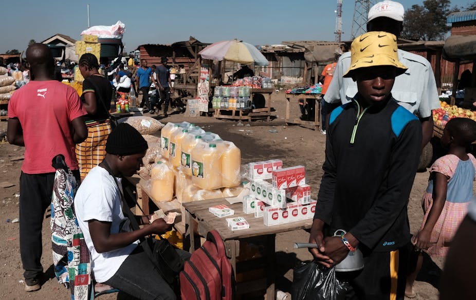 Roadside vendors sell goods at tables.