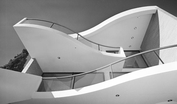 This may contain: a modern house with curved walls and glass balconies on the upper floor is shown in black and white