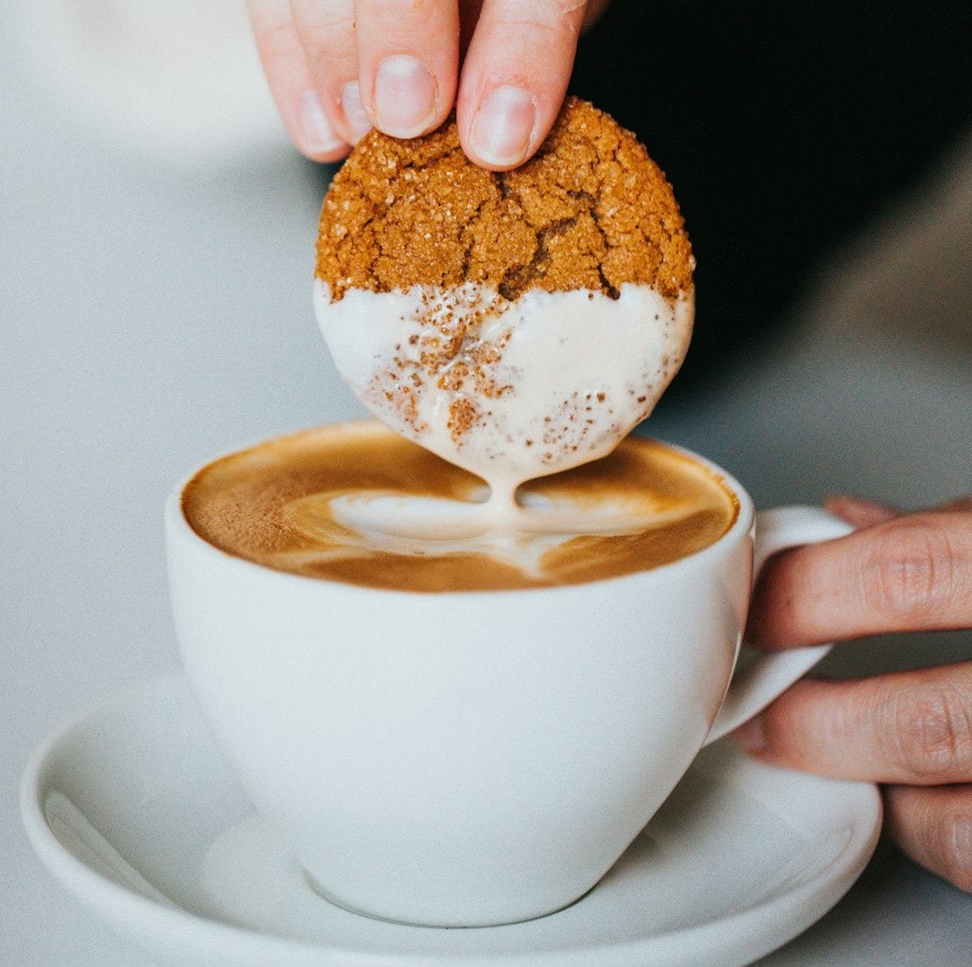 person holding white ceramic mug with brown and white liquid person holding white ceramic mug with brown and white liquid