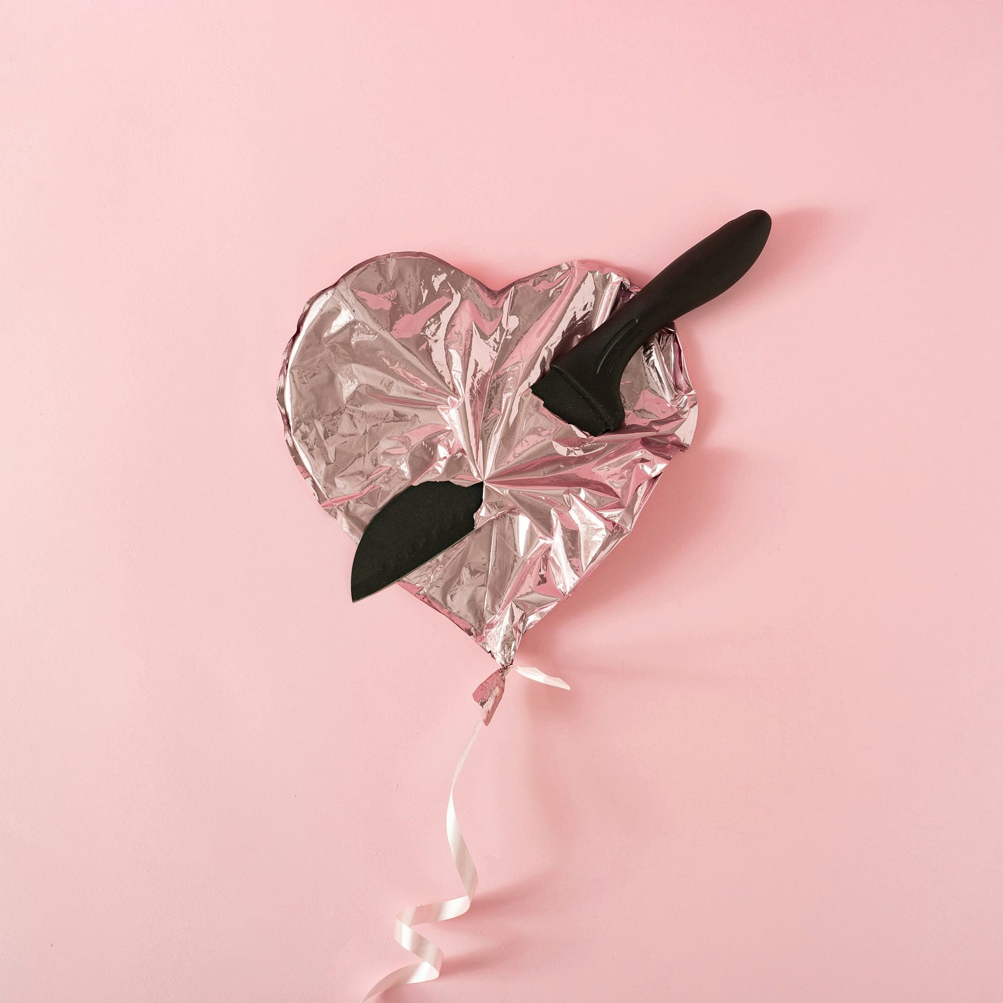 a knife through a foil heart balloon