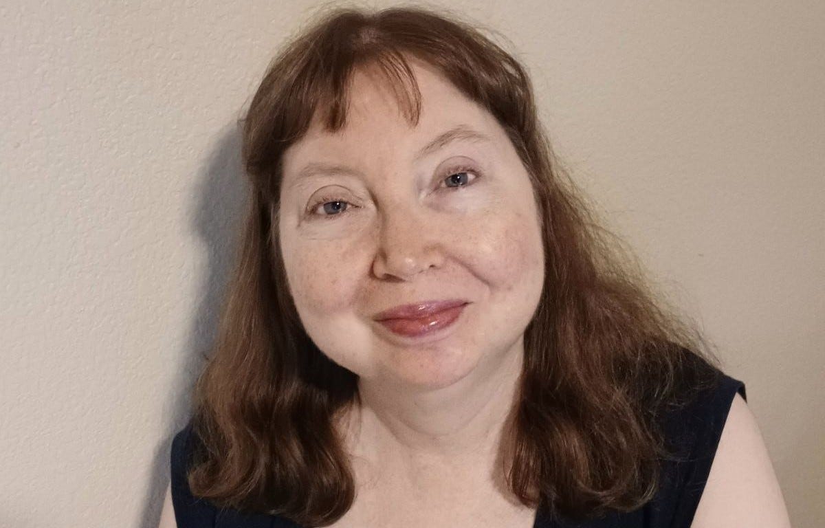 LightSome Lena, a woman with shoulder length auburn hair and blue eyes, wearing a short sleeved black dress LightSome Lena, a woman with shoulder length auburn hair and blue eyes, wearing a short sleeved black dress