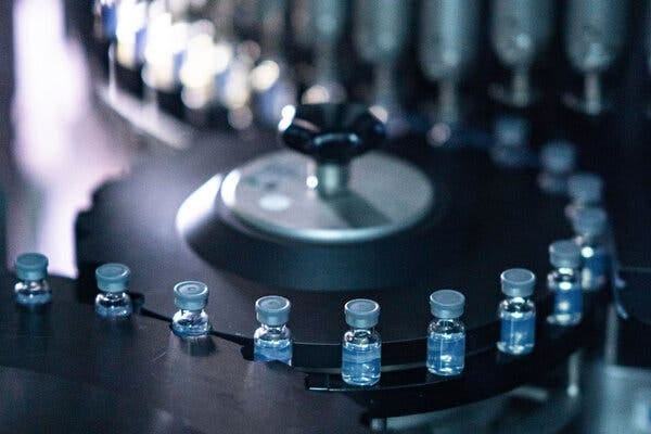 A close-up view of a row of light blue vials on a circular assembly line.