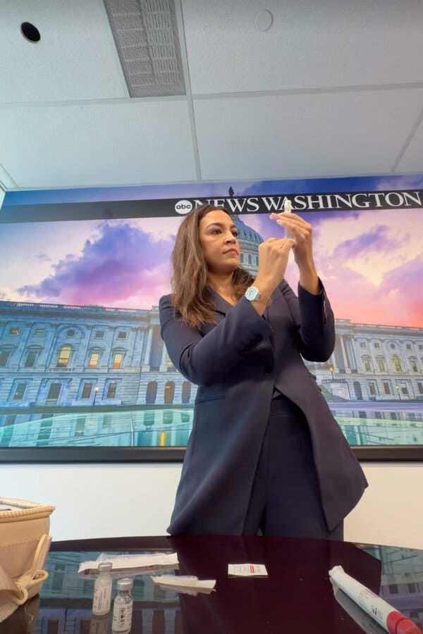 Ms. Ocasio-Cortez stands in an office, with a needle in her hand. Ms. Ocasio-Cortez stands in an office, with a needle in her hand.