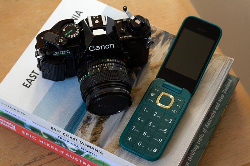 An old Canon camera and new but old style Nokia on a pile of travel-related books.