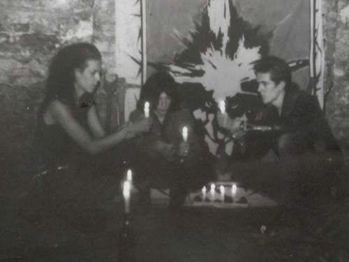 This may contain: black and white photograph of three people sitting at a table with candles in front of them
