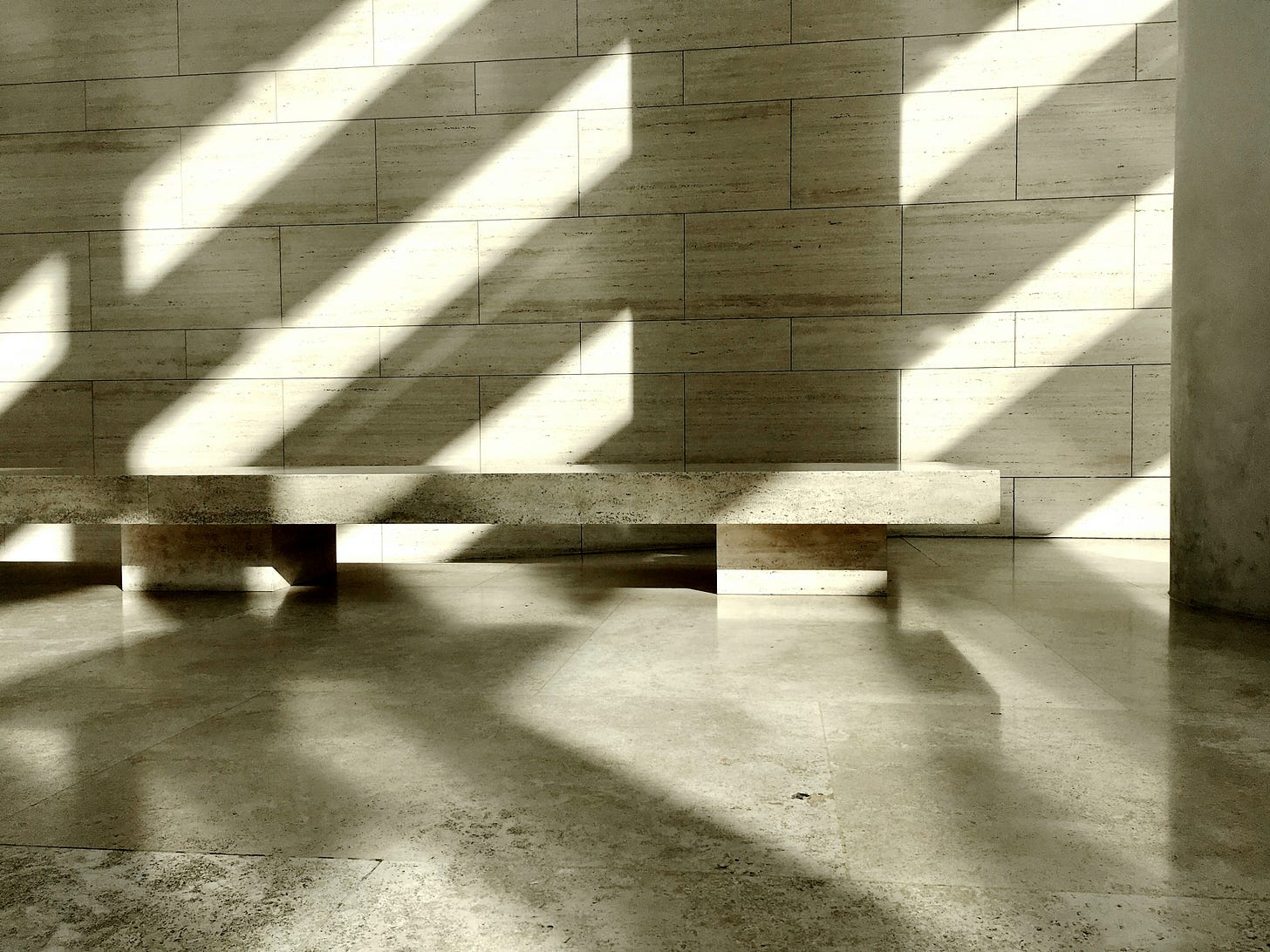 Sunlight casting long shadows across a matte stone wall and minimalist concrete bench. Sunlight casting long shadows across a matte stone wall and minimalist concrete bench.